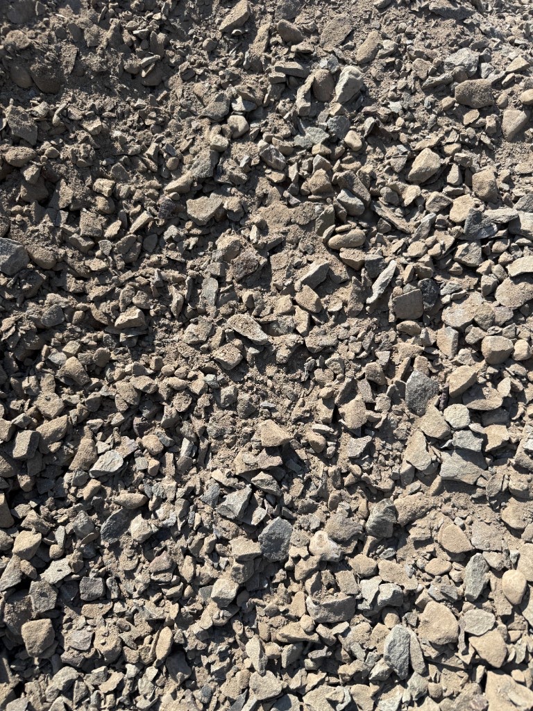 Crusher run: dense gray angular crushed stone suitable for compacted base layers.